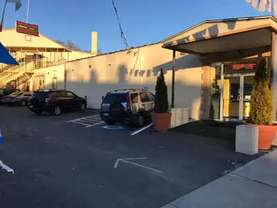 a parking lot with cars parked in front of a building at Waterbury Big Apple Motel in Waterbury