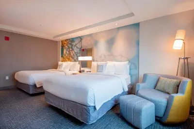 a hotel room with two beds and a chair at Courtyard by Marriott New York Queens/Fresh Meadows in Queens
