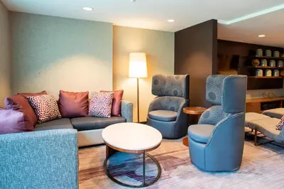 a living room with a couch and two chairs at Courtyard by Marriott New York Queens/Fresh Meadows in Queens