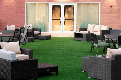 a patio with chairs and tables and green grass at Courtyard by Marriott New York Queens/Fresh Meadows in Queens