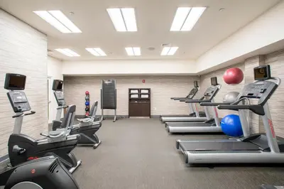 a gym with a row of treadmills and machines at Courtyard by Marriott New York Queens/Fresh Meadows in Queens