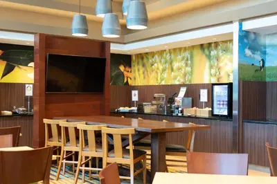 a restaurant with a large wooden table and chairs at Fairfield Inn & Suites by Marriott New York Queens/Fresh Meadows in Queens