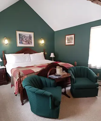 a bedroom with a bed and two chairs and a table at Arlington Inn & Spa in Arlington