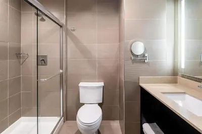 a bathroom with a toilet and a shower and a sink at Best Western Premier NYC Gateway Hotel in North Bergen