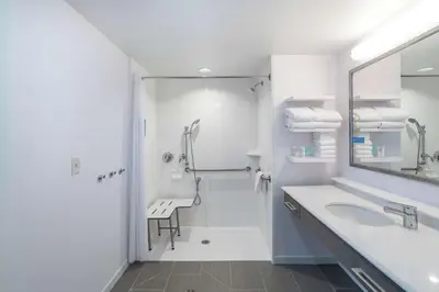 a white bathroom with a shower and a sink at Hampton Inn & Suites Newburgh Stewart Airport, NY in Newburgh