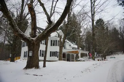 a white house with a tree in the snow at The Wilmington Inn in Wilmington