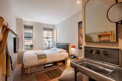 a bedroom with a bed and a sink and a mirror at Moxy NYC Times Square in New York