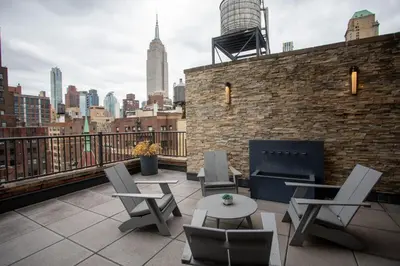 a rooftop patio with chairs and tables and a city skyline at Lexington Plaza Hotel in New York