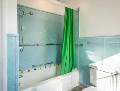 a bathroom with a green shower curtain and a toilet at Higganum House B&B in Higganum