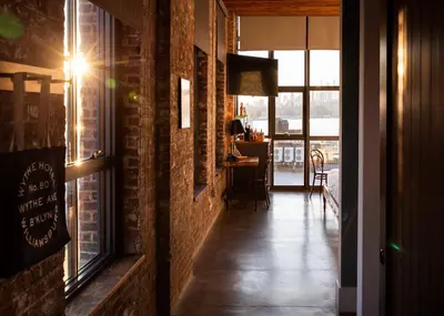 a room with a brick wall and a hallway with a window at Wythe Hotel in Brooklyn