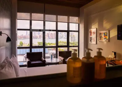 a living room with a large window with a view at Wythe Hotel in Brooklyn
