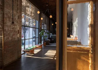 a room with a brick wall and a hallway with benches at Wythe Hotel in Brooklyn