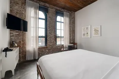 a bedroom with a white bed and a brick wall at Wythe Hotel in Brooklyn