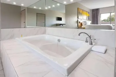 a large white bath tub in a bathroom at Days Inn & Suites by Wyndham Albany in Albany