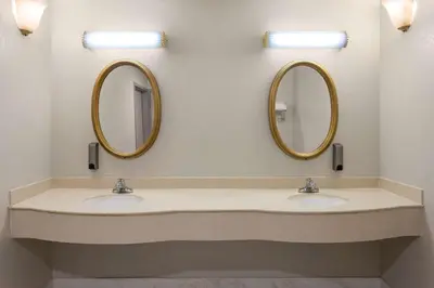 two sinks in a bathroom with two mirrors at Days Inn & Suites by Wyndham Albany in Albany