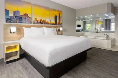 a hotel room with a bed and a bath tub at Days Inn & Suites by Wyndham Albany in Albany