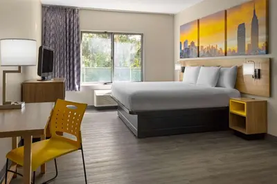 a hotel room with a bed and a desk and a computer at Days Inn & Suites by Wyndham Albany in Albany
