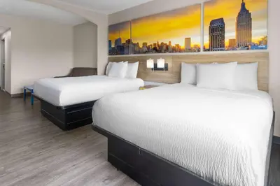 a hotel room with two beds and a painting at Days Inn & Suites by Wyndham Albany in Albany