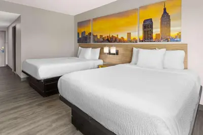 a hotel room with two beds and a painting on the wall at Days Inn & Suites by Wyndham Albany in Albany