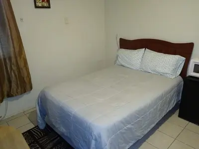 a bedroom with a white bed with a wooden headboard at Two Bedroom Apartment - North East Bronx in Bronx