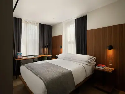 a bedroom with a bed and a desk and windows at The Moore, New York City, a Member of Design Hotels in New York