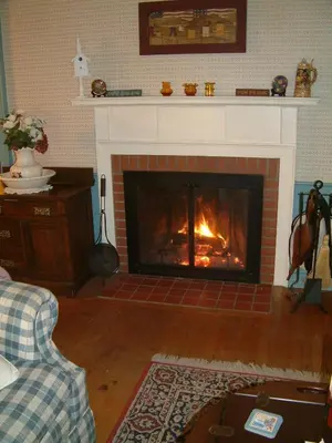 a living room with a fireplace with a fire in it at Truman Gillet House B & B in Granby