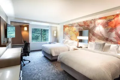 a hotel room with two beds and a flat screen tv at Courtyard by Marriott Lenox Berkshires in Lenox