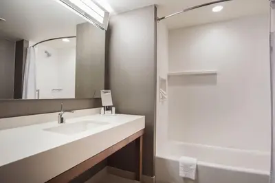 a bathroom with a sink and a mirror and a tub at Courtyard by Marriott Lenox Berkshires in Lenox