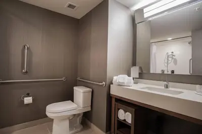 a bathroom with a toilet and a sink and a mirror at Courtyard by Marriott Lenox Berkshires in Lenox