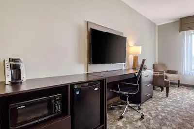 a hotel room with a desk with a television and a chair at Sleep Inn & Suites Middletown - Goshen in Middletown