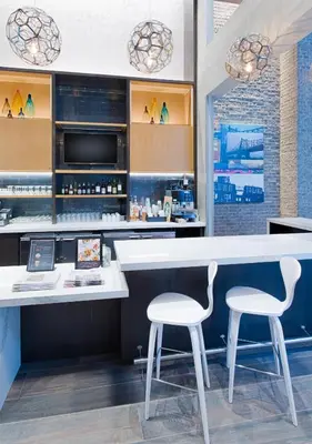 a bar with two white stools and a counter at Hyatt Place Long Island City in Queens