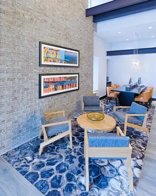 a lobby with tables and chairs and a brick wall at Hyatt Place Long Island City in Queens