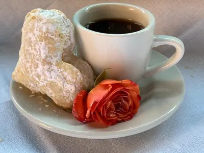 a cup of coffee and a donut and a rose on a plate at The Country Inn in Stone Ridge