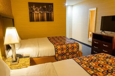 a hotel room with two beds and a flat screen tv at Elmhurst Hotel in Queens