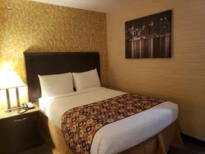 a hotel room with a bed and a lamp on a table at Elmhurst Hotel in Queens