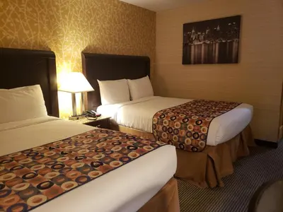 a hotel room with two beds and a lamp at Elmhurst Hotel in Queens