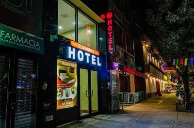 a hotel sign on the side of a street at night at Elmhurst Hotel in Queens