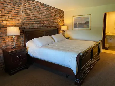 a bedroom with a bed and a brick wall at Chalet Inn & Suites in Centerport
