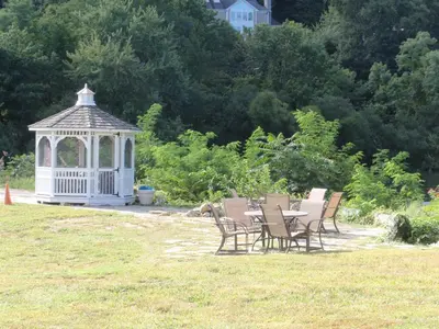 a gazebo with chairs and a table in a garden at Chalet Inn & Suites in Centerport