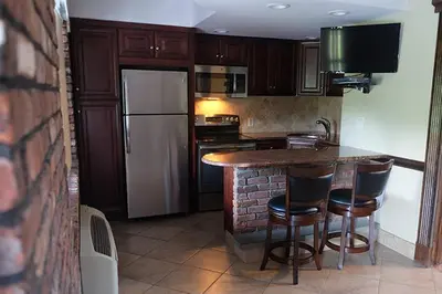 a kitchen with a counter with chairs and a refrigerator at Chalet Inn & Suites in Centerport