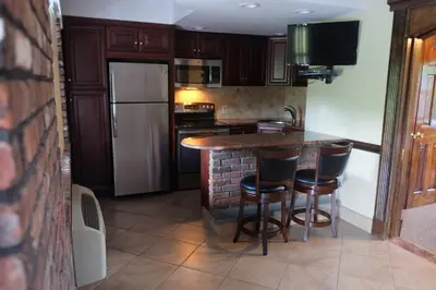 a kitchen with a bar with stools and a refrigerator at Chalet Inn & Suites in Centerport