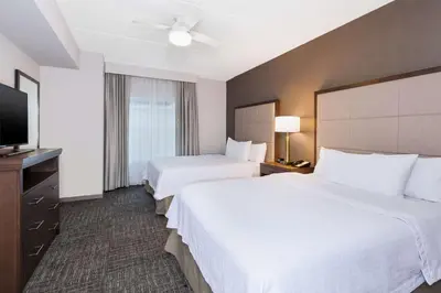 a hotel room with two beds and a flat screen tv at Homewood Suites By Hilton Saratoga Springs in Saratoga Springs
