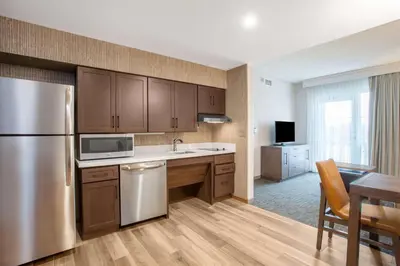a kitchen with a stainless steel refrigerator and a table at Homewood Suites By Hilton Saratoga Springs in Saratoga Springs