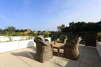 a patio with wicker chairs and a table on a balcony at Delamar West Hartford in West Hartford