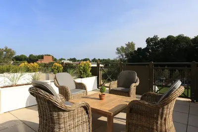 a patio with wicker chairs and a wooden table at Delamar West Hartford in West Hartford