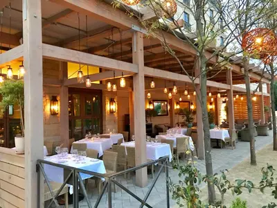 a restaurant with white tables and chairs and lights at Delamar West Hartford in West Hartford