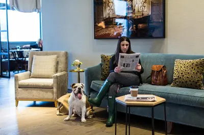 a woman sitting on a couch next to a dog at Delamar West Hartford in West Hartford