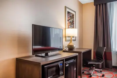 a hotel room with a flat screen tv and a desk at Comfort Inn & Suites near Stadium in Bronx