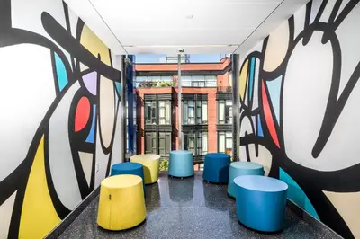 a hallway with colorful stools and a mural at Pod Brooklyn in Brooklyn