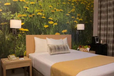 a bedroom with a bed and a painting of yellow flowers at Adria Hotel and Conference Center in Queens